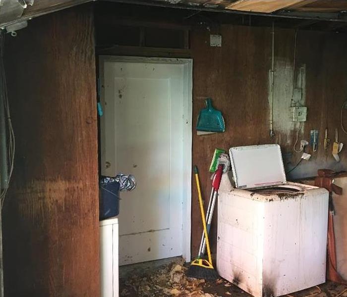 debris and burn marks on a white washing machine in a garage