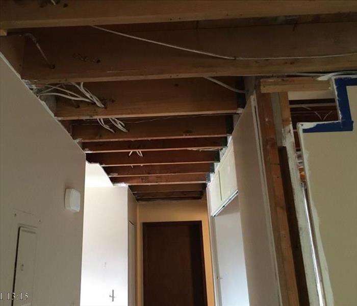 A hallway with sheetrock removed from the ceiling and some walls in anticipation of rebuilding