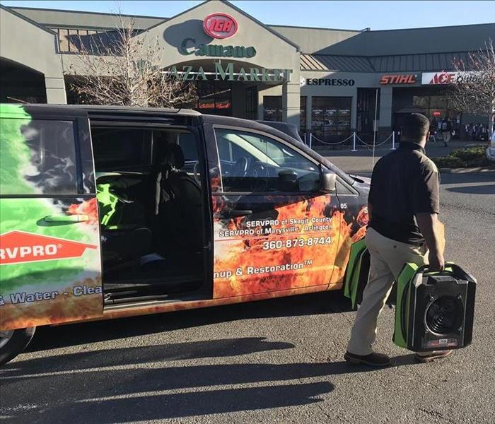 SERVPRO worker carrying equipment by vehicle