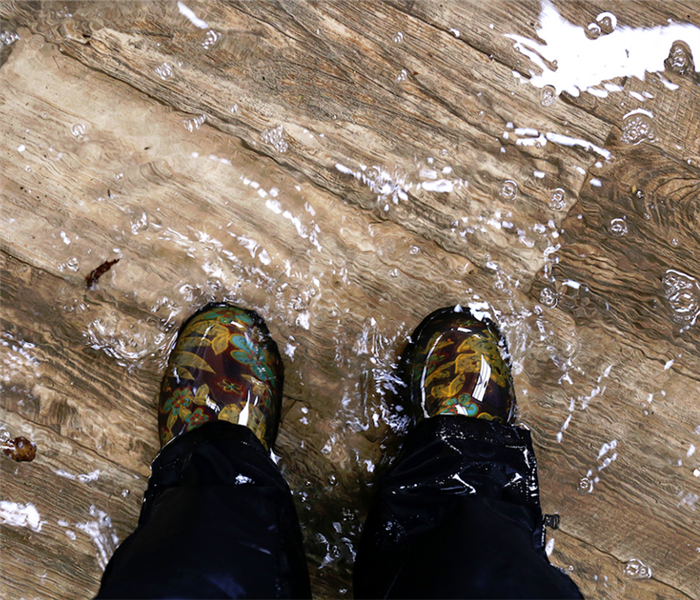 a flooded room with someone standing in it with water boots