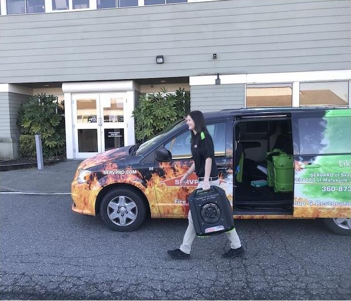 SERVPRO employee carrying water damage equipment from a van