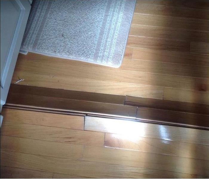 water damaged hardwood floor under cabinet; warping seen