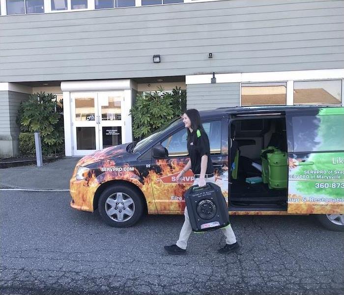 SERVPRO employee carrying water damage equipment from a van